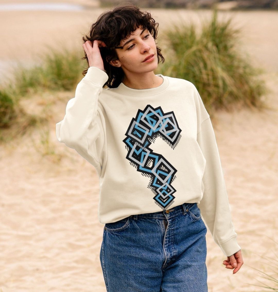 Woman wearing a cream graphic sweatshirt with blue geometric design and blue jeans, Comfy Elegance